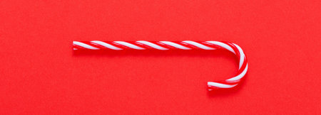 Christmas striped toy cane on red backgroundの写真素材