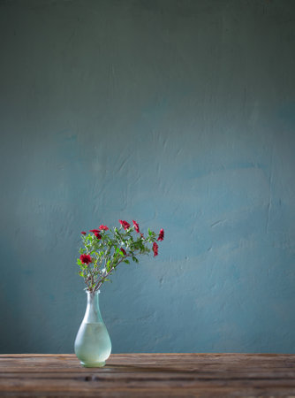 red chrysanthemums in glass vase on dark backgroundの写真素材