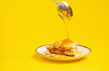 cake with honey on plate on yellow backgroundの写真素材