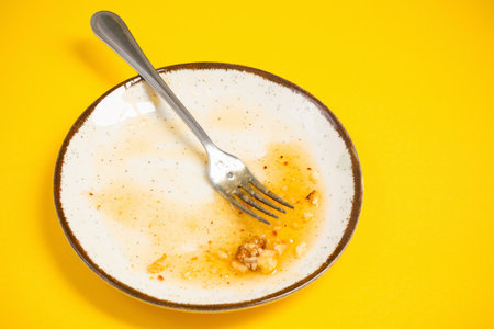 dirty plate with honey and pie crumbs on yellow backgroundの写真素材