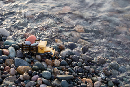 toy wooden car on the sea beach with rocks at sunsetの写真素材