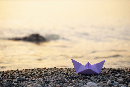 paper boat by the sea at sunsetの写真素材