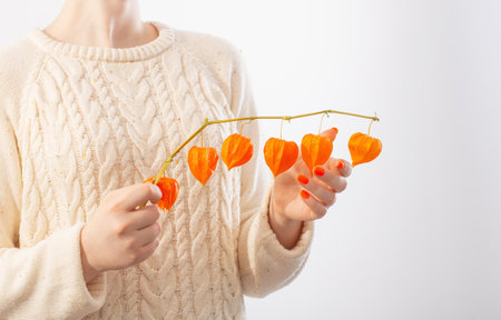 young woman with orange manicure with physalis on white backgroundの写真素材