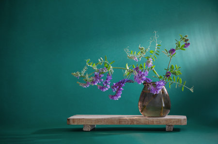 wild purple flowers in glass vase on green backgroundの写真素材