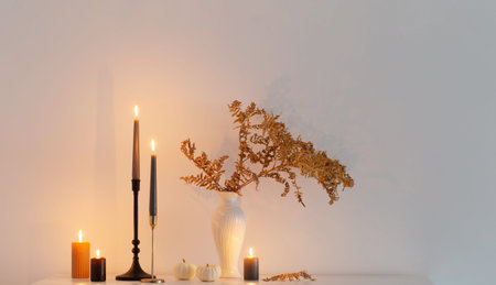 beautiful autumn home decor with burning candles in white interiorの写真素材