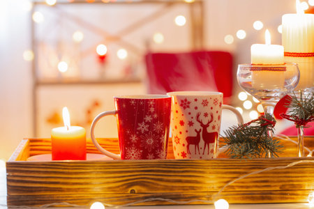 cup of hot drink with christmas decorations in white and red colors at homeの写真素材