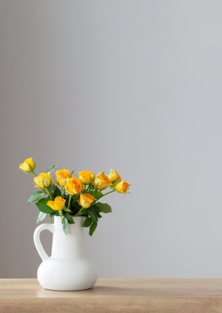 yellow roses in white jug on wooden shelfの写真素材