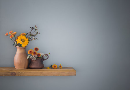 autumn flowers in rustic ceramic vase on background gray wallの写真素材