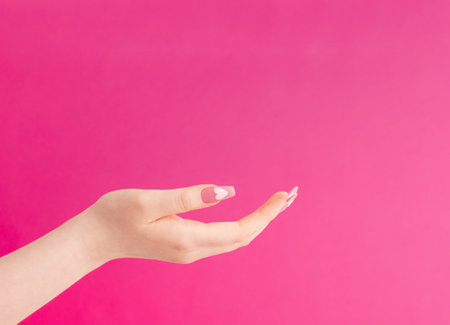 female hands with beautiful long nails with manicure with heart pattern on pink backgroundの写真素材