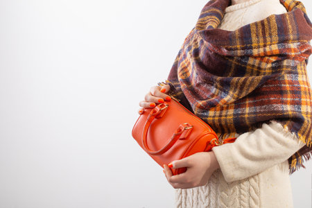 woman in knitted sweater with orange handbag on white backgroundの写真素材