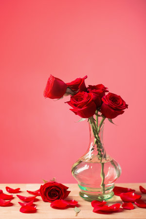 red roses in glass vase on red backgroundの写真素材