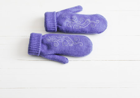 purple mittens on white wooden background