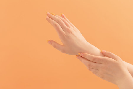 female hand with manicure on peach backgroundの写真素材