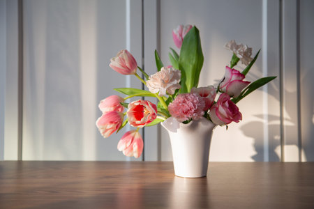 pink spring flowers in white ceramic vase in modern home interior