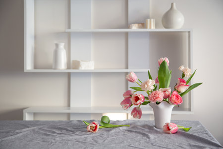 pink spring flowers in white ceramic vase in modern home interiorの写真素材