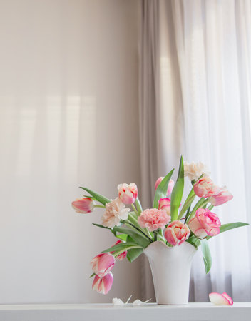pink spring flowers in white ceramic vase in modern home interiorの写真素材