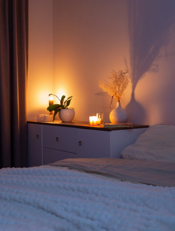 burning candles with flowers in vase in bedroom at nightの写真素材