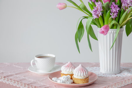 cup of tea and cupcakes with spring flowers in light colorsの写真素材