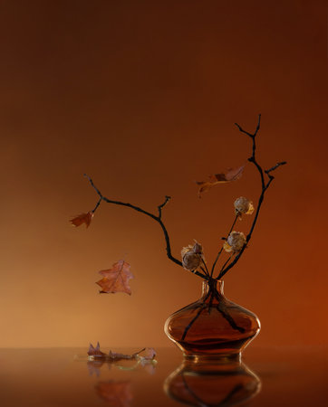autumn still life with dried roses and oak leaves in glass vaseの写真素材