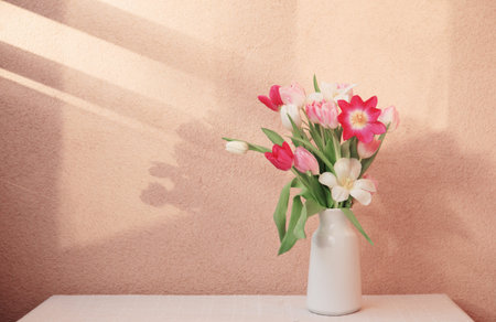 tulips in vase on table on background wallの写真素材