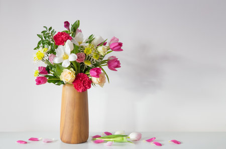 beautiful flowers in vase on shelf on background white wallの写真素材