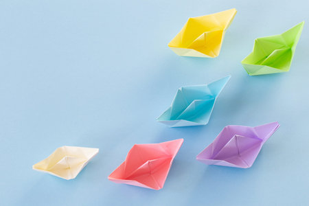 color paper boats on blue background