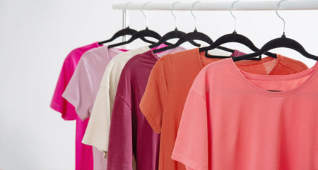 row of t-shirts on a hanger against a background of a white wall hangerの写真素材