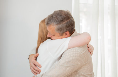 father and daughter hugging against white wallの写真素材