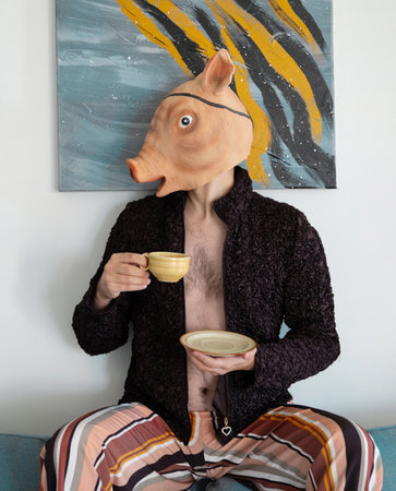 man in rubber pig mask with cup on background wallの写真素材