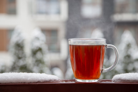 glass cup of tea in snow on balcony in winterの写真素材