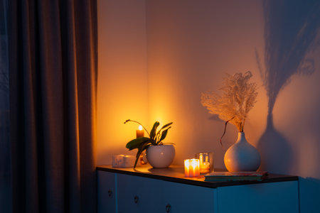 burning candles with flowers in vase in bedroom at nightの写真素材