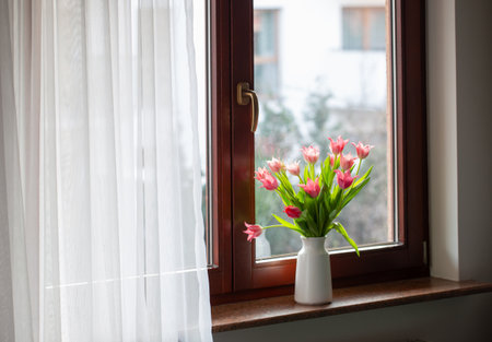 pink tulips in vase on windowsillの写真素材