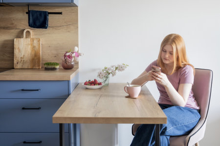young blonde woman with cup of tea in the kitchenの写真素材