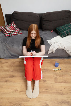 girl sitting on the floor at home and painting a picture by numbers painting by numbersの写真素材