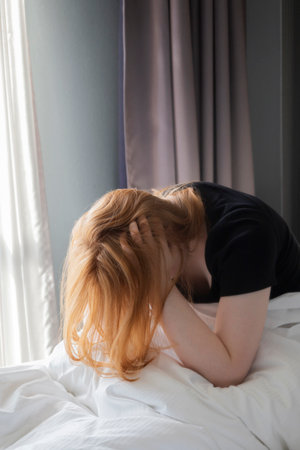 unhappy young woman in bedroom close upの写真素材
