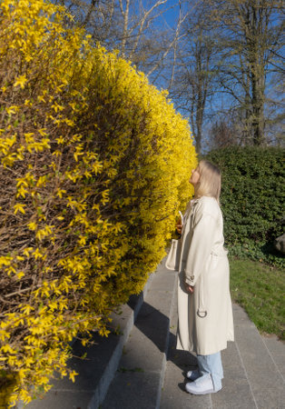 blonde woman take a picture on smartphone in spring parkの写真素材