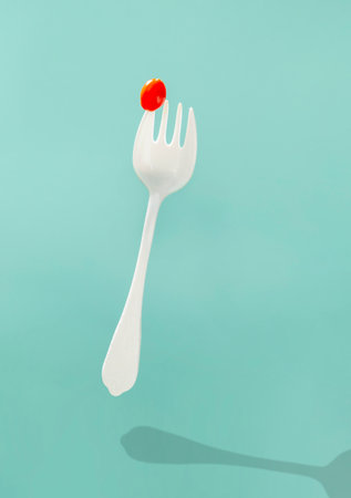little red tomato on big white forkの写真素材