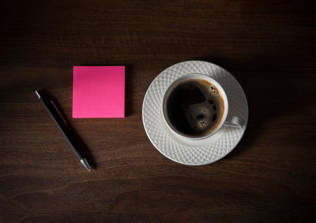 cup of coffee with paper on dark wooden background