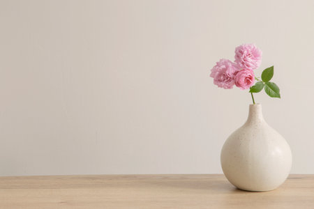 pink roses in ceramic vase on wooden tableの写真素材