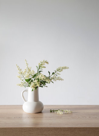 white lilac flowers in vase on wooden tableの写真素材