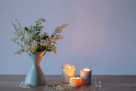 white lilac flowers in vase with burning scened candlesの写真素材