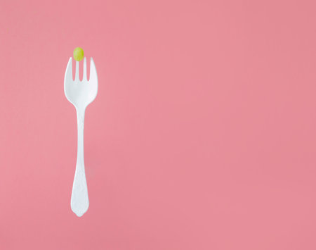 green grape on big white fork on pink backgroundの写真素材