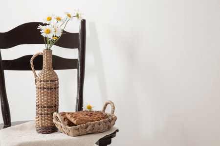 daisies in a vintage bottle and baked goods in a basket on a vintage chairの写真素材
