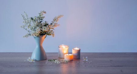 white lilac flowers in vase with burning scened candles