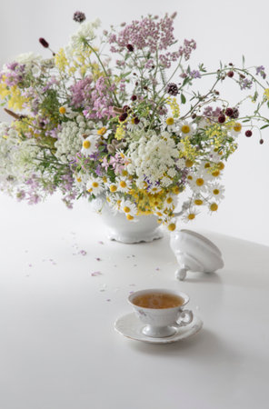 cup of tea with wild flowers on white tableの写真素材