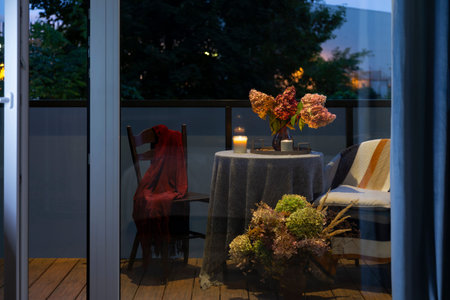flowers in a vase on a table on a city balcony in the eveningの写真素材