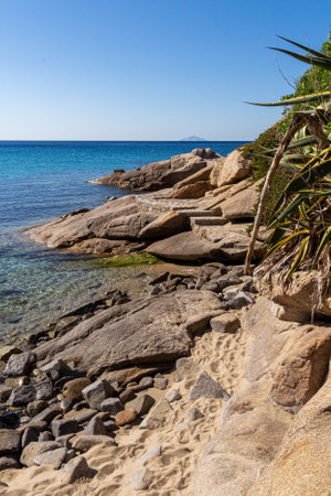 Sandy little beach with big rocks at Seccheto, Elba Island, Italy. In background island of Montecristo.の写真素材