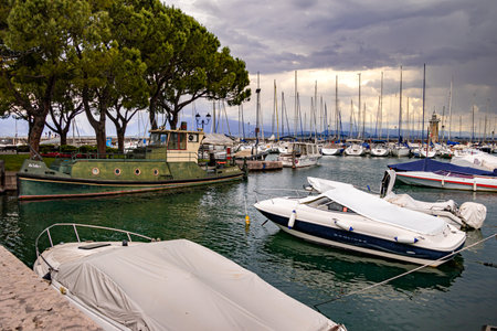Desenzano, Lake Garda, Italy - 25 May 2024 Colorful motor- and sailingboats and lighthouse at harborのeditorial素材