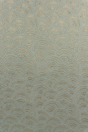 Close-up of decorative light olive-beige brocade fabric featuring the motif with yellow metallic...