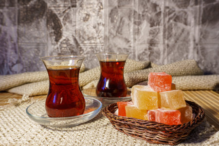 Two glasses of turkish tea and a small woven basket with colorful rahat lokum. Shot in oriental style, made on a wooden background, using textilesの写真素材
